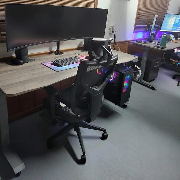 adjustable sit to stand desk in office setup with large wide screen, chair and CPU tower hanger 