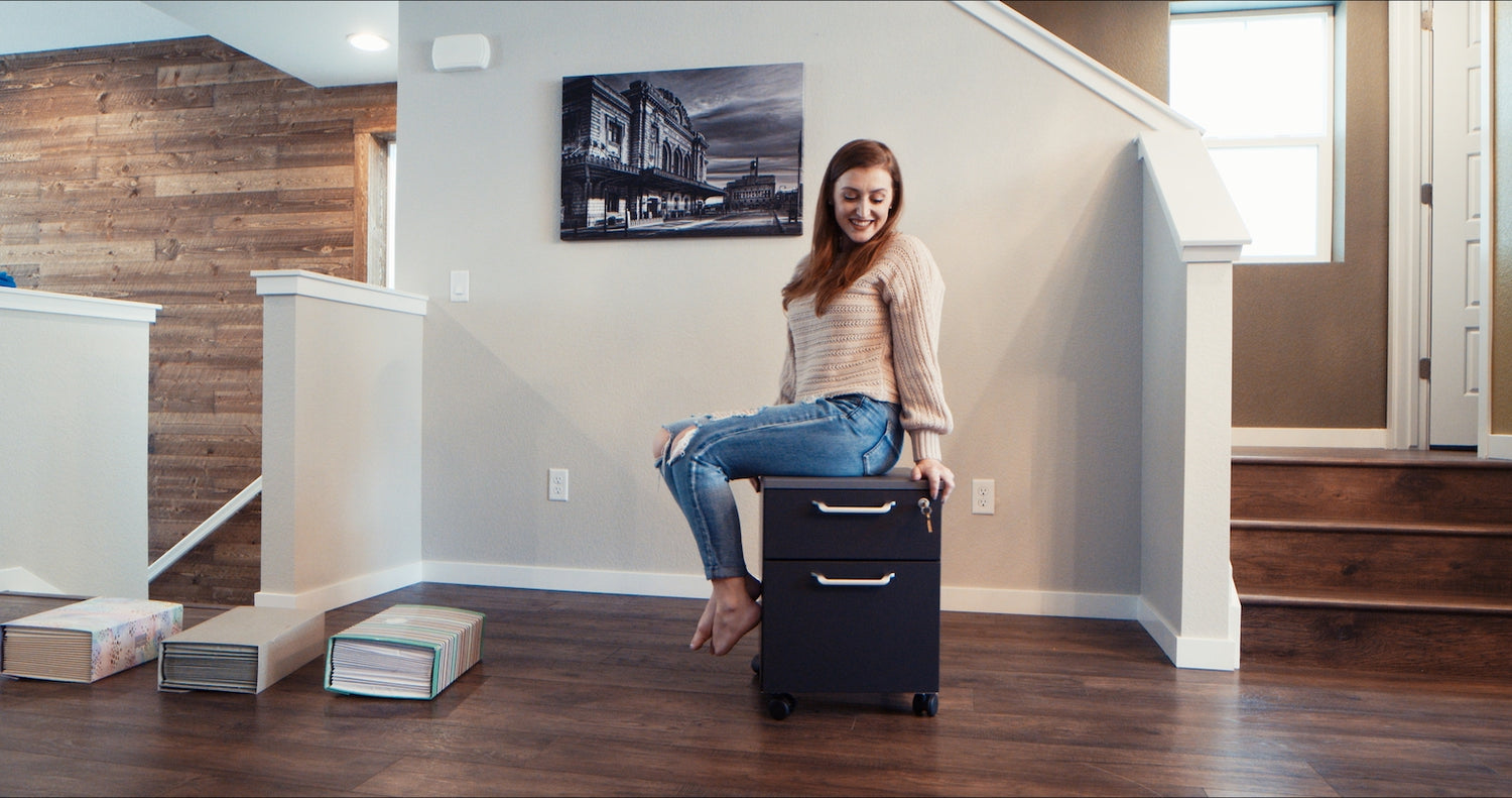 Mobile Storage for Standing Desk shown with woman sitting on top