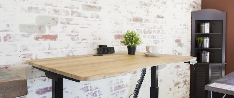height adjustable sit stand desk with plant and coffee cup in front of white brick wall coffee shop